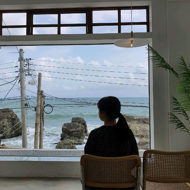 카페 우리집 통창 앞 좌석 — 오션뷰를 바라보는 실루엣