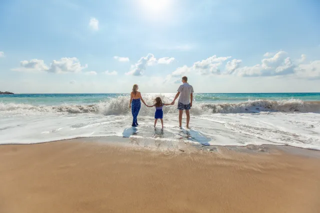 Семья гуляет по солнечному пляжу