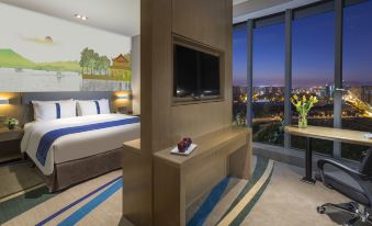The bedroom features large windows and a centrally positioned bed, providing a view of the outdoors from within at Holiday Inn Express Hangzhou East Station