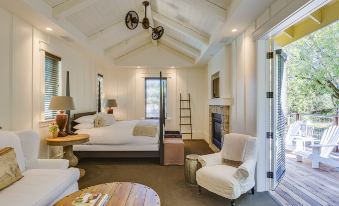 a cozy bedroom with a white bed , a chair , and a ladder leading to a loft area at Farmhouse Inn