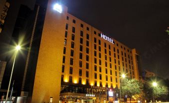 "a large hotel building lit up at night , with its name "" hotel "" illuminated in blue lights" at M Hotels