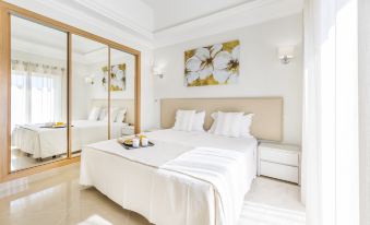 a large white bed with a tray of snacks on it is in a bedroom with two lamps at Lakeside Country Club - Apartamentos Turísticos