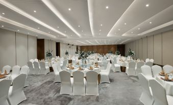 A ballroom is arranged for an event, with tables and chairs placed in the center at Grand Barony Qingdao Airport Hotel