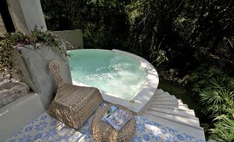 a hot tub is surrounded by a rug and two wicker chairs , with trees in the background at Proud Phu Fah Maerim Resort