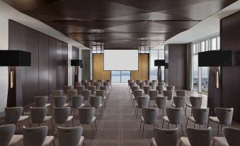 A spacious room with rows of chairs facing the front, accompanied by an empty conference table at Andaz Shenzhen Bay