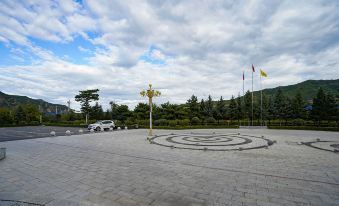 a city park with a paved walkway , benches , and a parking lot where a car is parked at Frontier Building