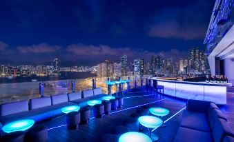 At night, a city's illuminated skyline is complemented by waterfront tables on top at The Park Lane Hong Kong a Pullman Hotel