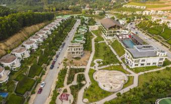a bird 's eye view of a residential area with green spaces , roads , and buildings , including a pool at Ivory Villas & Resort