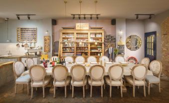 a long dining table surrounded by white chairs in a restaurant setting , with several bottles of liquor on display at Amble Hotel