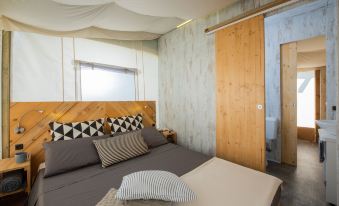 a cozy bedroom with a wooden bed , a window , and a door leading to a bathroom at Hu Montescudaio Village