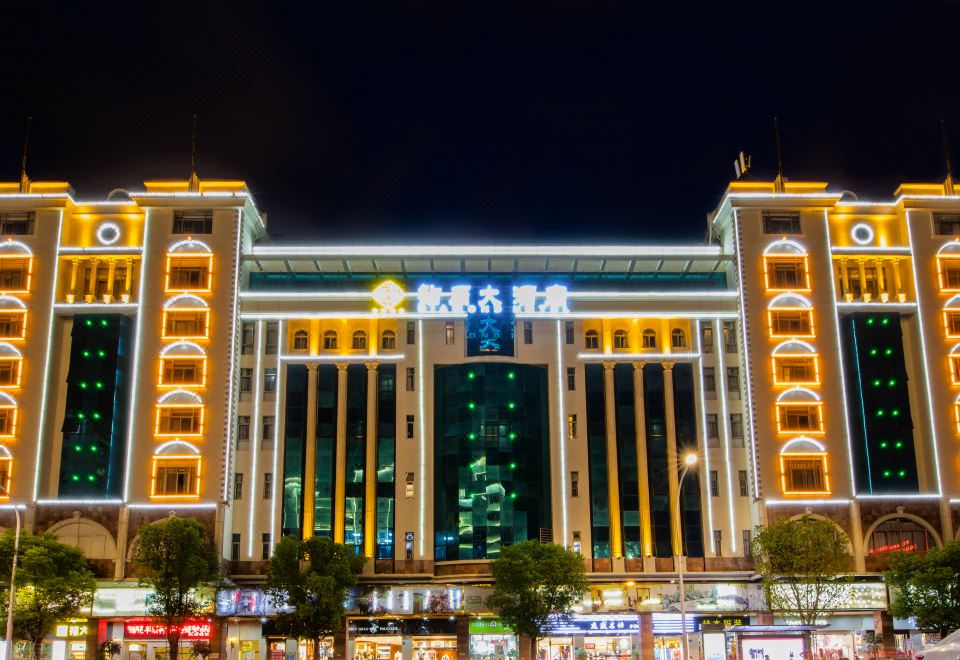 a large shopping mall with multiple levels and elevators , illuminated at night , surrounded by trees at Diamond Hotel