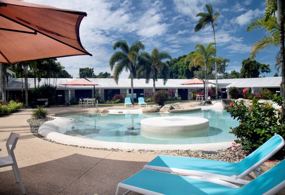 a resort with a large pool surrounded by lounge chairs and palm trees , providing a relaxing atmosphere for guests at Mission Beach Resort