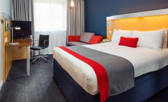 a modern hotel room with a red and white bed , blue walls , and a tv at Holiday Inn Express Stevenage