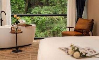 A bedroom with large windows and a balcony offers a view of the city, featuring an unmade bed at Foshan Lanshan Hotel (Shunde Qinghuiyuan)