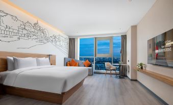 A modern bedroom with large windows features a white bed and a chair positioned in the center at UrCove by HYATT Nanjing South Railway Station