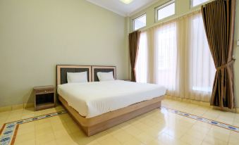 a large , neatly made bed with a wooden headboard is in the center of a room with a window and curtains at Super OYO Collection O 2383 Andongkoe 64 Salatiga