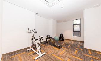 a gym room with exercise equipment , including a treadmill and weights , on a wooden floor at Ibis Styles Hotel