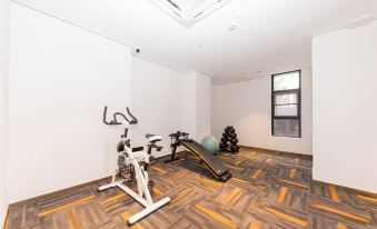 a room with a treadmill , stationary bike , and exercise equipment on a carpeted floor , along with white walls and a window at Ibis Styles Hotel
