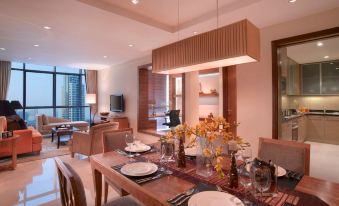 a dining room with a table set for a meal , surrounded by chairs and a television at Oakwood Premier Cozmo Jakarta