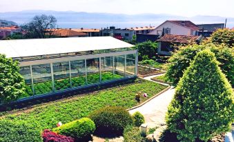 a large greenhouse filled with various plants and vegetables , surrounded by a lush garden and a view of the ocean at Augusta Eco Wellness Resort 4 - SPA Access included
