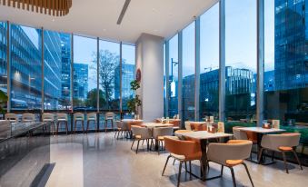 The restaurant features large windows and tables in the center, all offering a view of the sea at UrCove by HYATT Nanjing South Railway Station