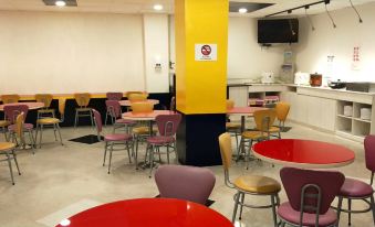 a brightly lit restaurant with several tables and chairs , a neon sign , and a yellow wall at 101 Hotel