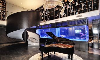 A spacious room features a grand piano and various artworks displayed on the wall behind it at Livefortuna Hotel