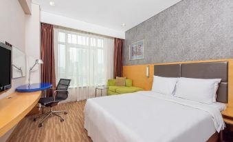 In the bedroom, there is a large bed, a desk, and an oversized chair by the window at Holiday Inn Express Beijing Dongzhimen