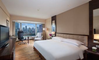 The bedroom features large windows that offer a view of the city, and there is an unmade bed in the room at The Kunlun Jing An