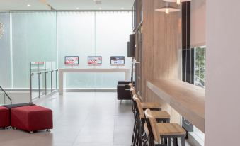 a modern waiting area with wooden tables , chairs , and a large window , providing a comfortable and inviting atmosphere for customers at Red Planet Manila Bay