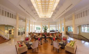 a large , open room with multiple couches and chairs arranged in a lounge setting , surrounded by tables and plants at Dheva Mantra Resort