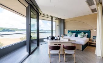 The bedroom, which has large windows and a balcony with an ocean view, features an island table in the front at WM HOTEL HONG KONG, Vignette Collection