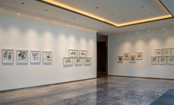 an empty room with white walls and a blue floor , where several framed drawings are displayed at Artels