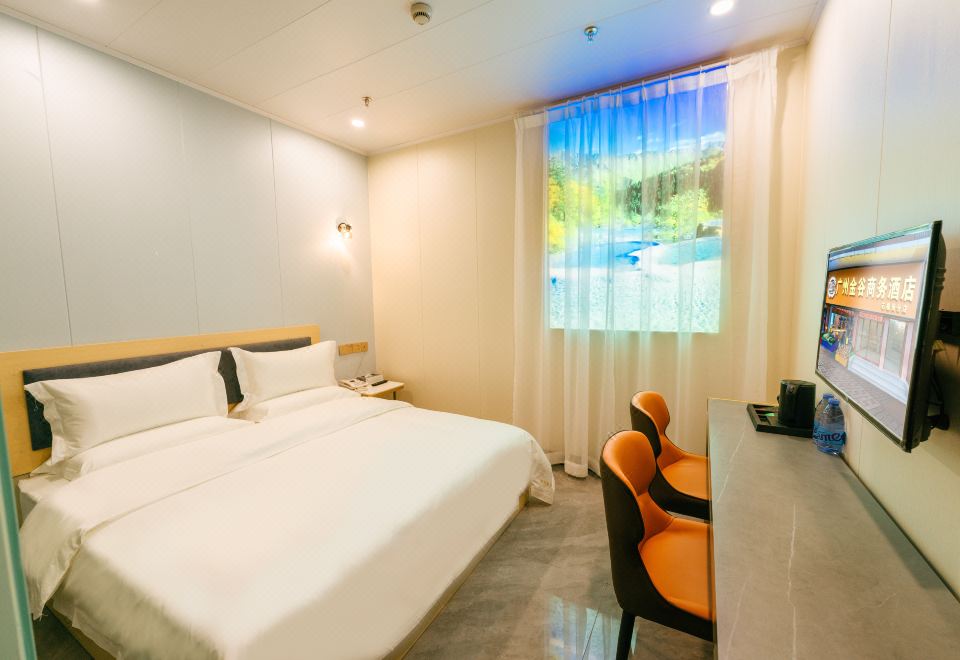 A bedroom with a double bed, desk, and chair is located by a large window at Jingu Business Hotel (Chigang Subway Station, Guangzhou Weizhou Convention and Exhibition Center)