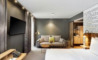 a modern living room with a couch , coffee table , and television mounted on the wall at HYPERION Hotel Leipzig