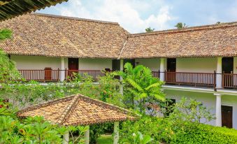 a traditional thai - style house with a thatched roof and balconies , surrounded by lush greenery and tropical plants at The Fortress Resort & Spa
