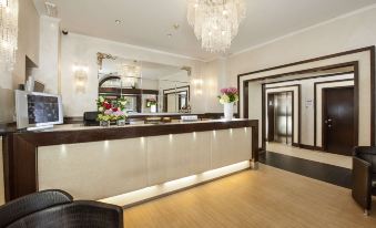 a hotel lobby with a wooden reception desk and a crystal chandelier hanging from the ceiling at Yes Hotel