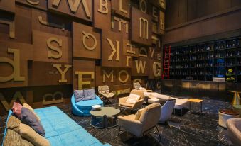 a modern living room with large wooden letters on the wall , a blue couch , and various seating options at M Hotel