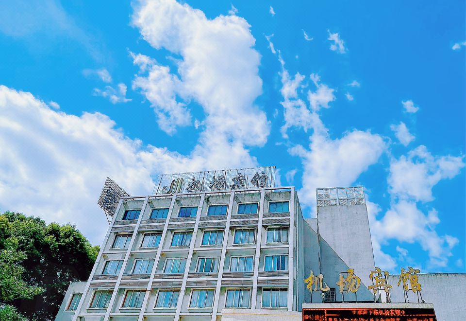 a large white building with a blue sky in the background and chinese characters on the sign at Airport Hotel