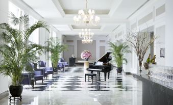 In the lobby, there are chairs and tables, and an elegant piano hangs from the ceiling at The Langham, Shenzhen