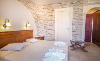 a cozy bedroom with a bed , nightstand , and door , decorated with white and beige walls at Naxos Palace Hotel