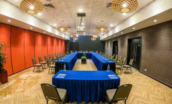 a large conference room set up for a meeting , with multiple tables and chairs arranged in a semicircle at Highlander Hotel & Apartments