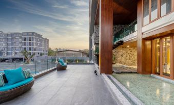 There is a balcony on the roof with chairs and tables that overlooks an outdoor swimming pool at Orion Hotel & Residence Bangna