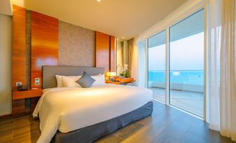 a large bed with white linens is in a room with wooden walls and floor - to - ceiling windows overlooking the ocean at Seashells Phu Quoc Hotel & Spa