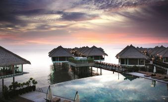 a resort with multiple buildings on stilts over the water , overlooking a pool and lounge chairs at Golden Palm Tree Sepang (formerly Avani Sepang Goldcoast Resort)