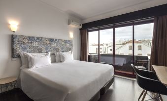 a large bed with white sheets is in a room with a window and a desk at AquaHotel