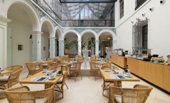 a large dining room with multiple tables and chairs arranged for a group of people to enjoy a meal together at H10 Palacio Colomera