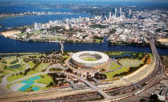 an aerial view of a city with a large stadium in the center surrounded by water and buildings at Quest Innaloo