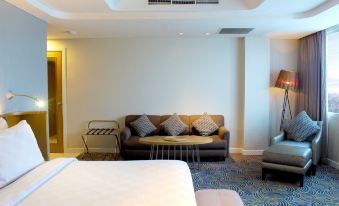 a hotel room with a bed , couch , and tv . also a chair in the room at Hotel Ciputra Cibubur Managed by Swiss-Belhotel International