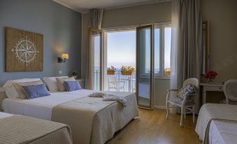 a bedroom with two beds , one on each side of the room , and a sliding glass door leading to a balcony at Hotel Punta Nord Est